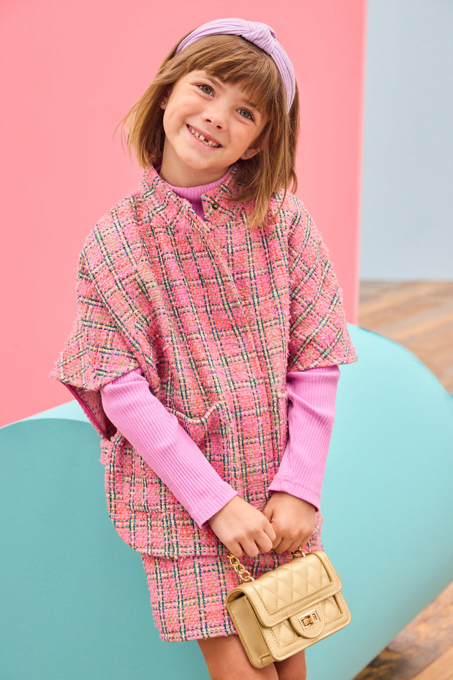 Model can be seen wearing tweed cape and skort in the matching magenta print, paired with a magenta ribbed turtleneck to complete the look. 