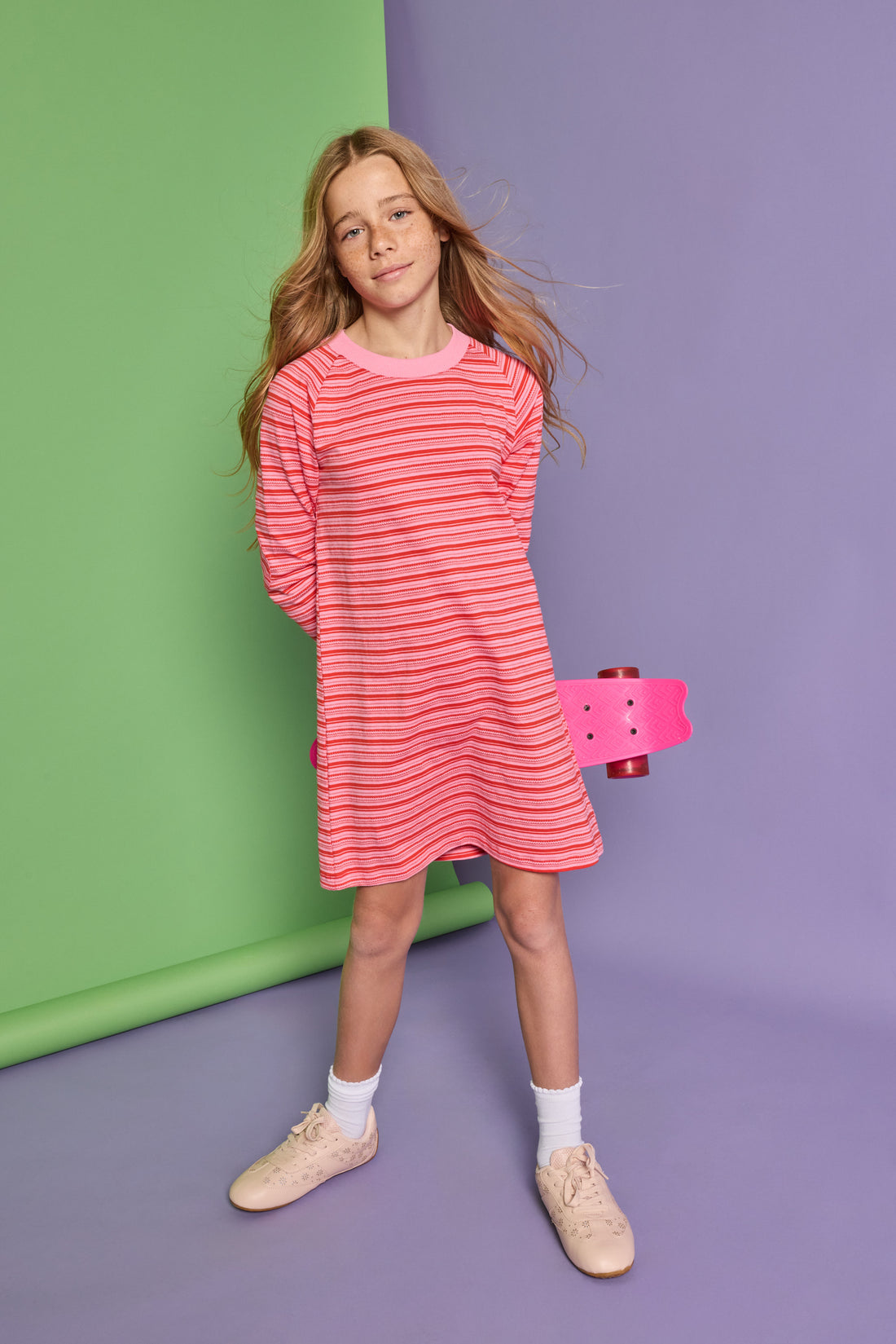 Model can be seen wearing a red and pink stripe knit dress. Dress features a thick pink neckline for an elevated look. 