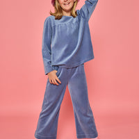 Model can be seen wearing a matching dusty blue velour set. Long sleeve top features button closure at back and pants feature pockets and an elastic waistband for a relaxed but secure fit. 