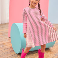 Model can be seen wearing a thicker knit long sleeve dress that features a mixed stripe detail in a magenta/pink/white pattern.