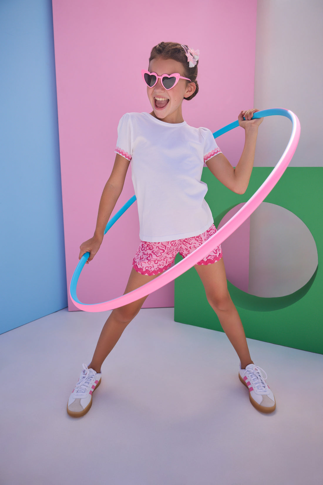 Model can be seen wearing white knit top that features hot pink/light pink ric rac detail at edge of sleeves to elevate the look. Top pairs back perfectly with woven hot pink/light pink ric rac shorts to complete the look. 