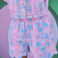Model can be seen wearing shirred shorts in a pink/blue floral print. Shorts feature smocking along waist and scallop edges to elevate the look. Shorts pair back perfectly with woven top in matching floral print to complete the look. 