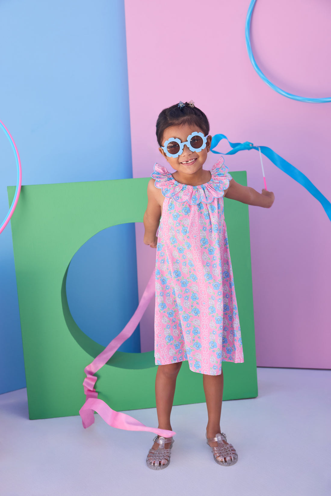 Model can be seen wearing a blue and pink floral woven dress that features an elastic scallop neckline detail to elevate the look.