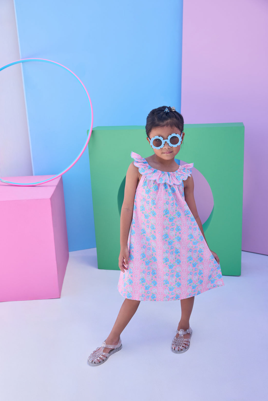 Model can be seen wearing a blue and pink floral woven dress that features an elastic scallop neckline detail to elevate the look.