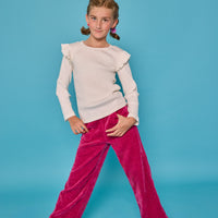 Model can be seen wearing fuchsia herringbone corduroy pants that feature pockets and an elastic waistband. Paired back with the white ribbed ruffle sleeve long sleeve shirt to complete the look. 
