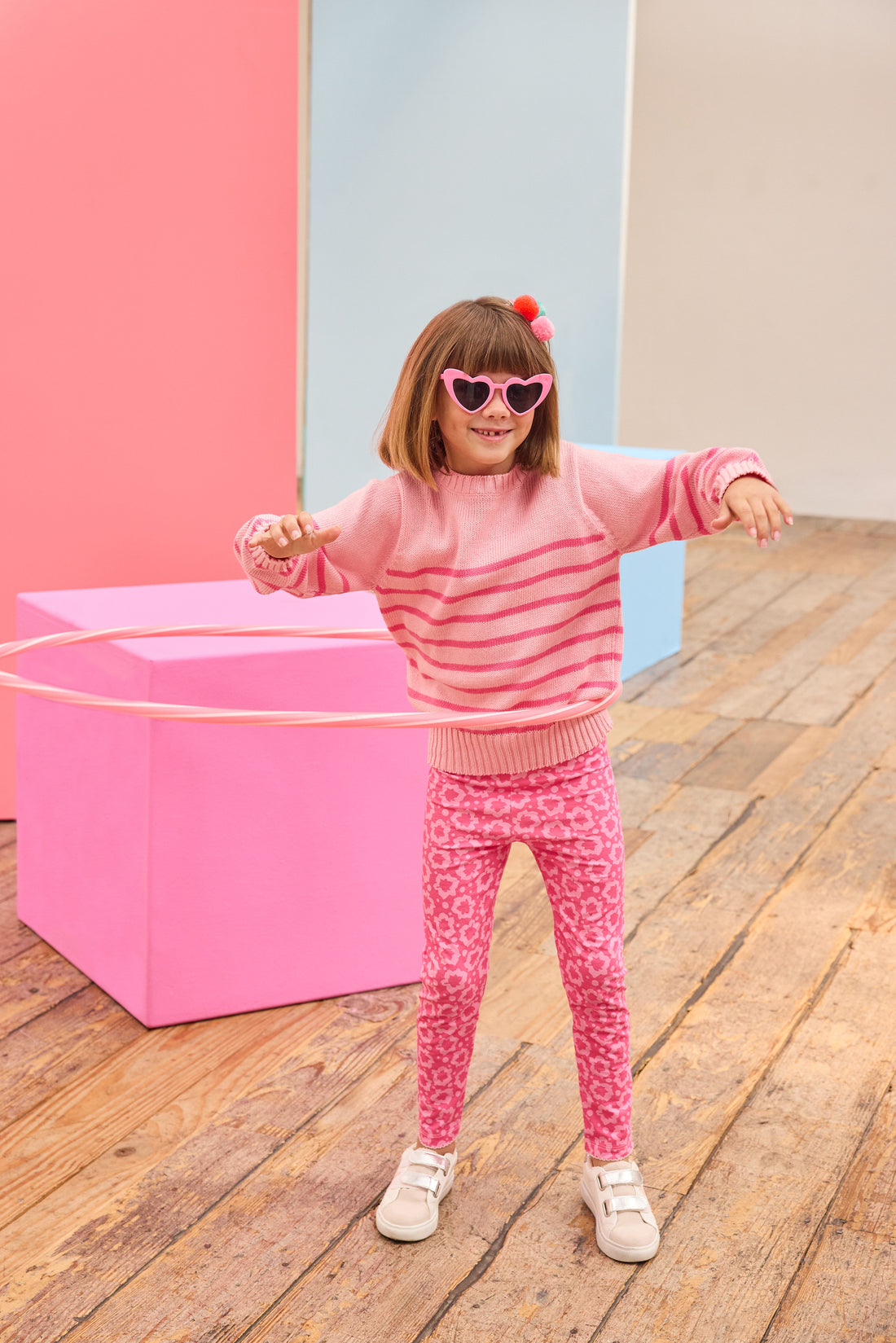 Tween model seen wearing a striped light pink and hot pink sweater paired back with leggings in a fun fall print. 