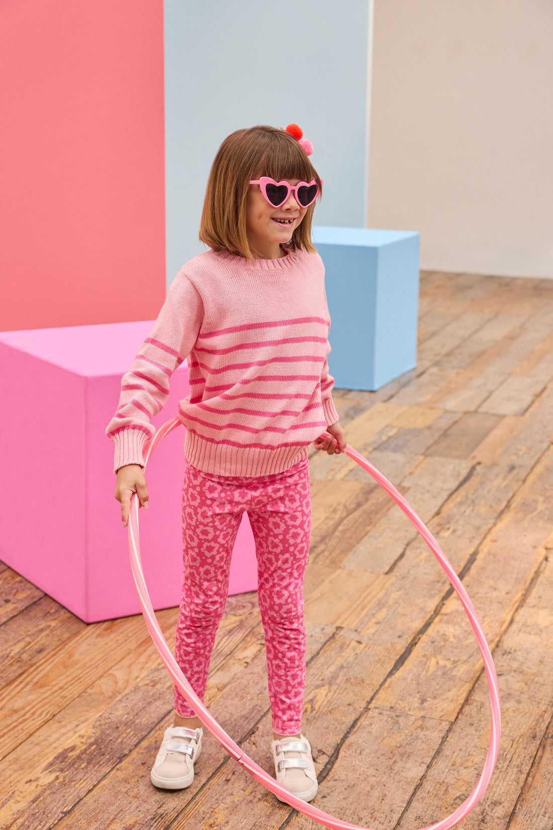 Tween model seen wearing a striped light pink and hot pink sweater paired back with leggings in a fun fall print. 