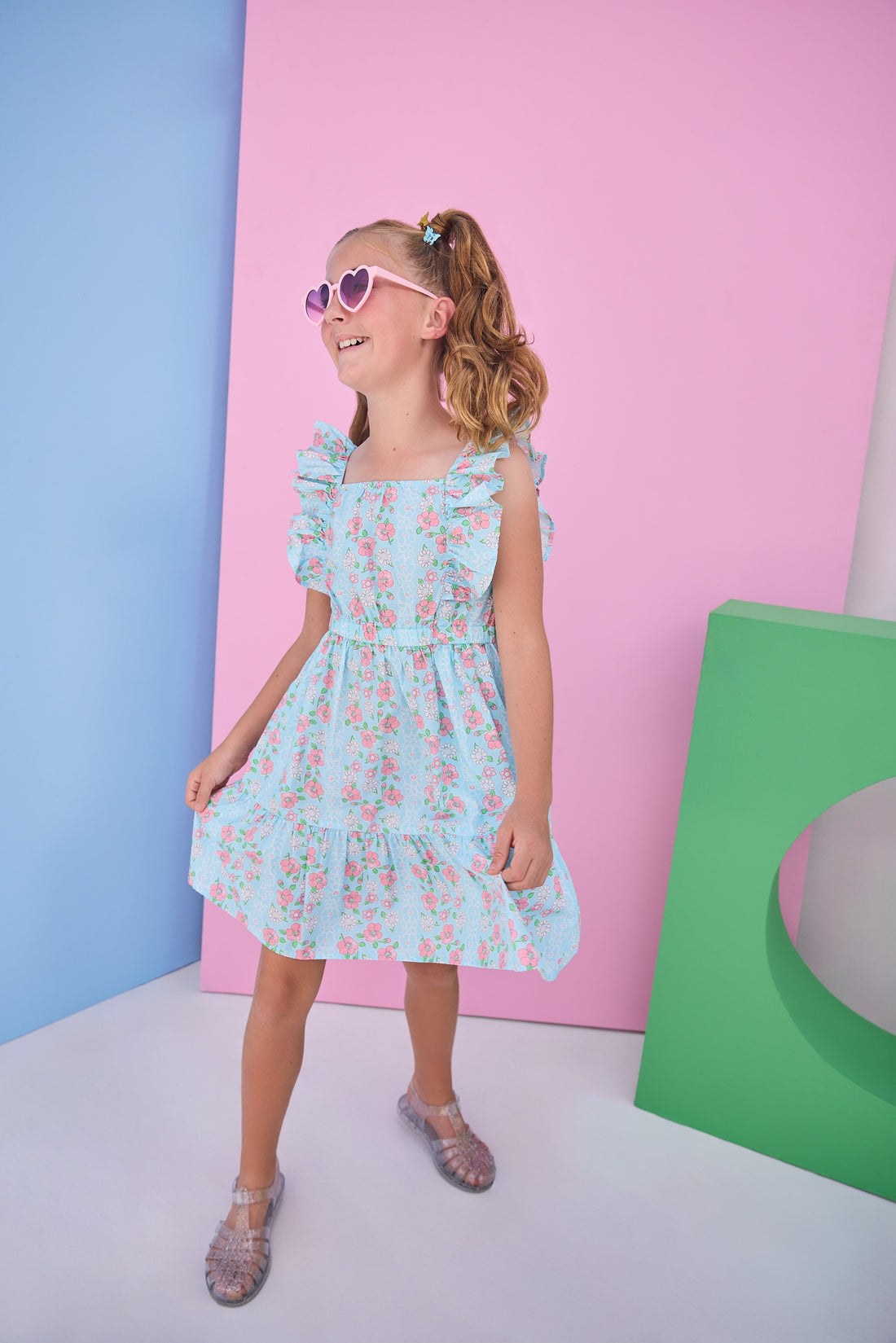 Tween model can be seen wearing a woven light blue/pink floral print that features an elastic waistband and angel flutter sleeves for a secure but comfy fit. 