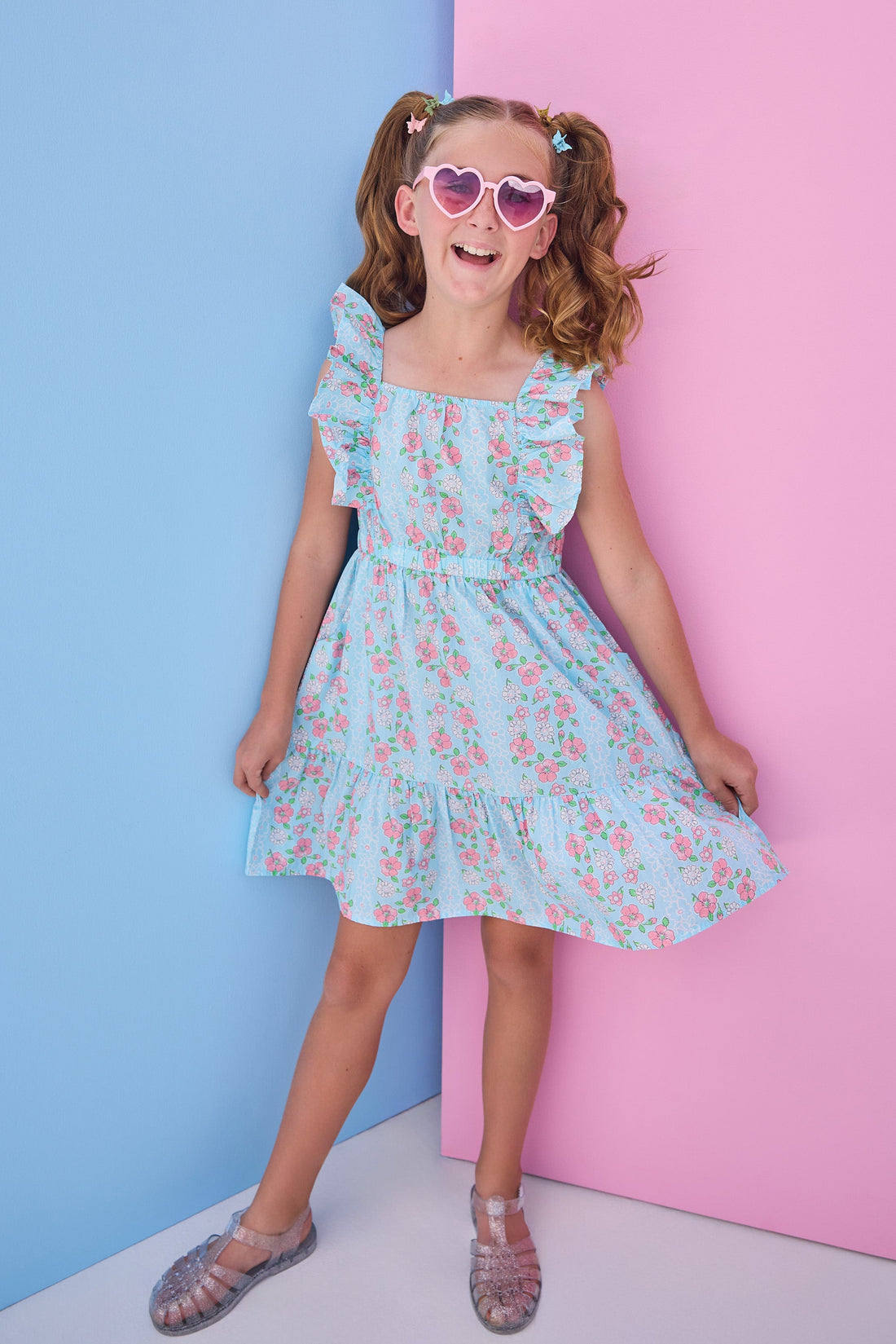 Tween model can be seen wearing a woven light blue/pink floral print that features an elastic waistband and angel flutter sleeves for a secure but comfy fit. 