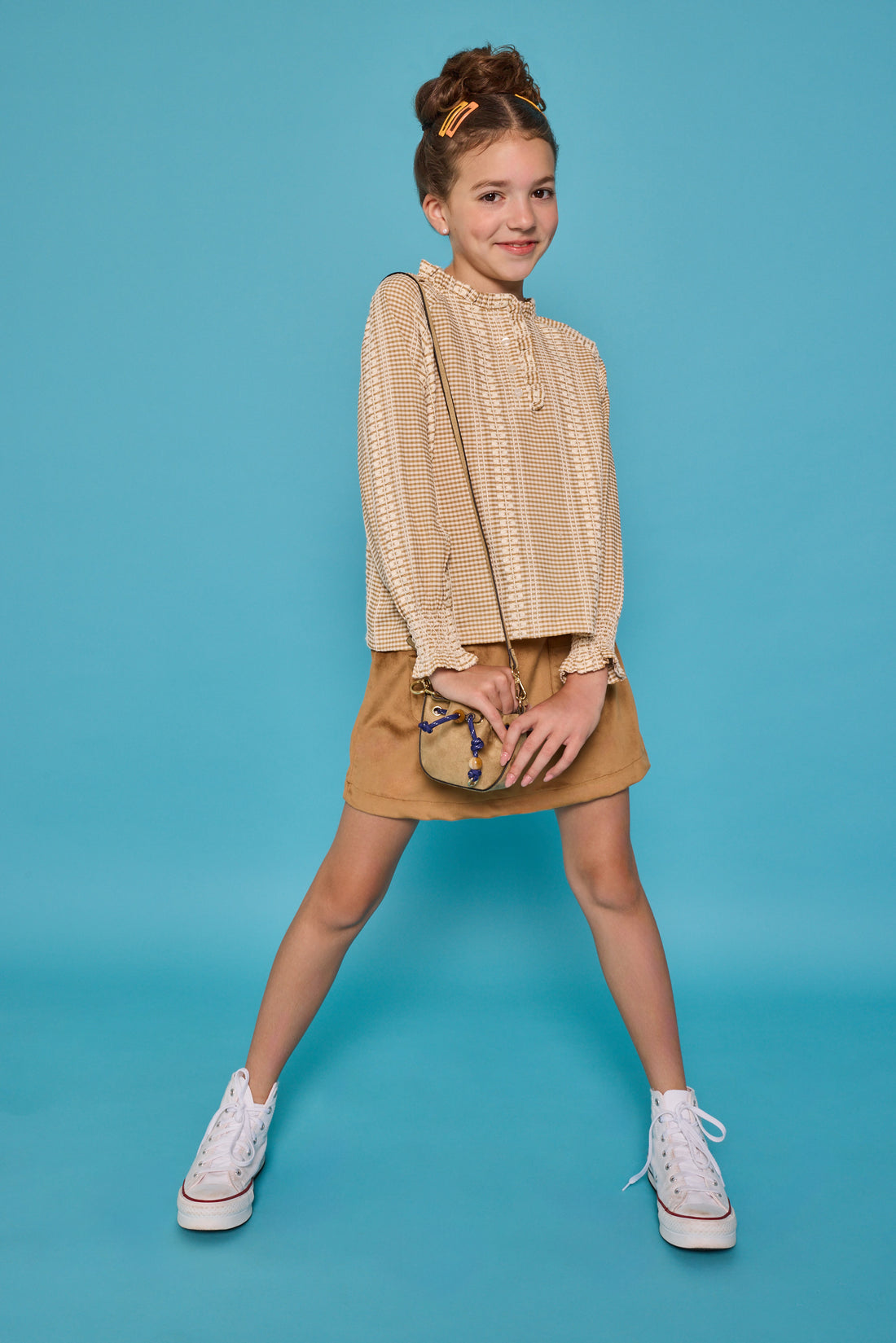 Model can be seen wearing a long sleeve woven top in a tan/cream  print. Top features button closure packet down bust and smocking detail at sleeves for an elevated look. Paired back with our brown faux suede skort that has built in shorts and pocket detail at front. 