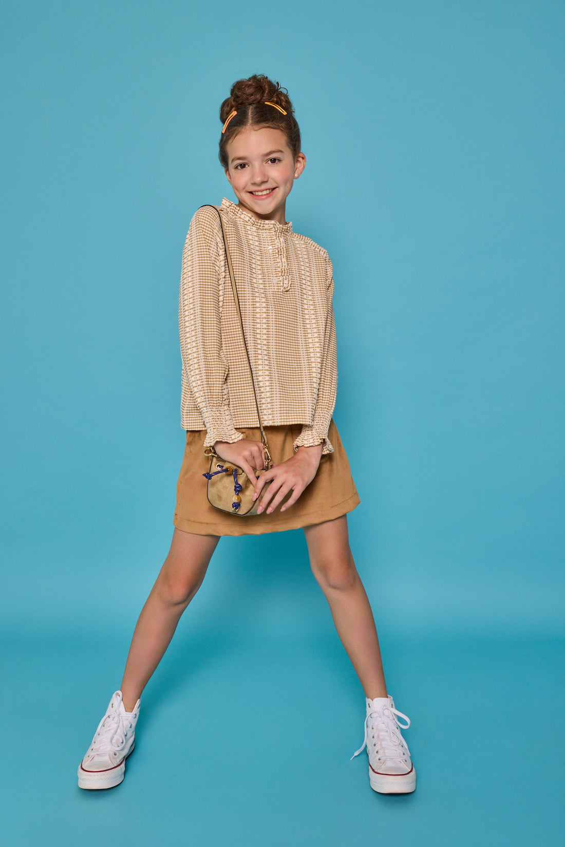 Model can be seen wearing a long sleeve woven top in a tan/cream  print. Top features button closure packet down bust and smocking detail at sleeves for an elevated look. Paired back with our brown faux suede skort that has built in shorts and pocket detail at front. 
