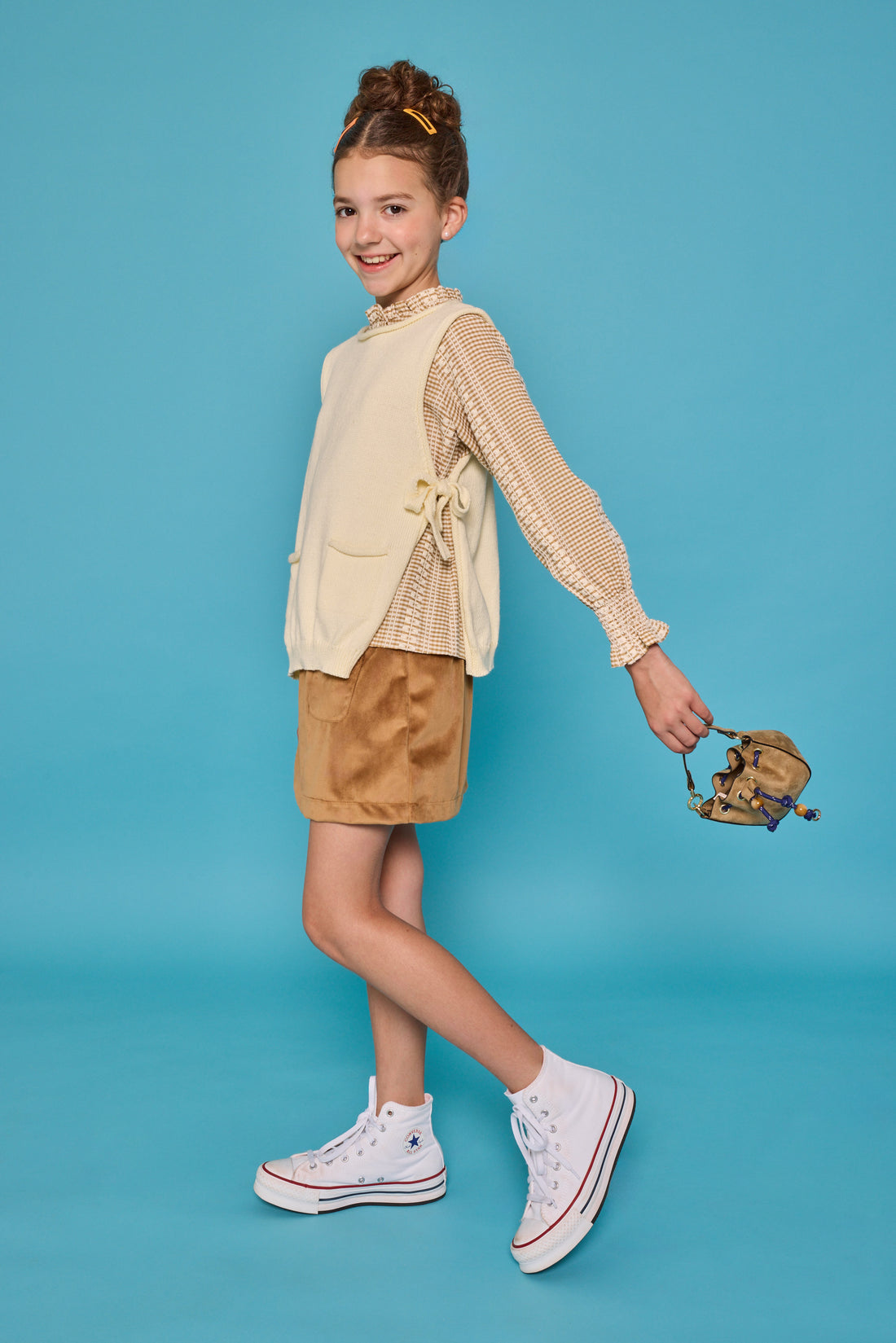 Model can be seen wearing tan/cream pattern woven top paired underneath a cream sweater vest with ties at sides for an elevated look. Paired back with our skort in brown faux suede to complete the look. 