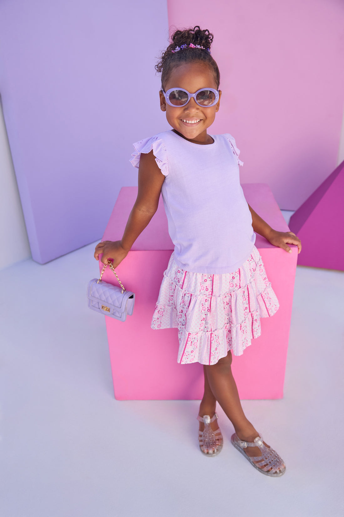 Model can be seen wearing lilac knit tee shirt that features an eyelet detail on the angel sleeve for an elevated look. Top pairs back perfectly with lilac/pink/white floral print skort. Skort features two tier detail, built in shorts, and elastic waistband for a secure but comfy fit. 
