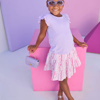 Model can be seen wearing lilac knit tee shirt that features an eyelet detail on the angel sleeve for an elevated look. Top pairs back perfectly with lilac/pink/white floral print skort. Skort features two tier detail, built in shorts, and elastic waistband for a secure but comfy fit. 