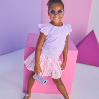 Model can be seen wearing lilac knit tee shirt that features an eyelet detail on the angel sleeve for an elevated look. Top pairs back perfectly with lilac/pink/white floral print skort. Skort features two tier detail, built in shorts, and elastic waistband for a secure but comfy fit. 