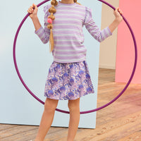 Model can be seen wearing blue/purple/white floral skort that features elastic ruching at the waist and built in shorts for a secure fit. Skort pairs back perfectly with striped ribbed top in purple/white/blue stripes. 