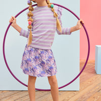 Model can be seen wearing blue/purple/white floral skort that features elastic ruching at the waist and built in shorts for a secure fit. Skort pairs back perfectly with striped ribbed top in purple/white/blue stripes. 