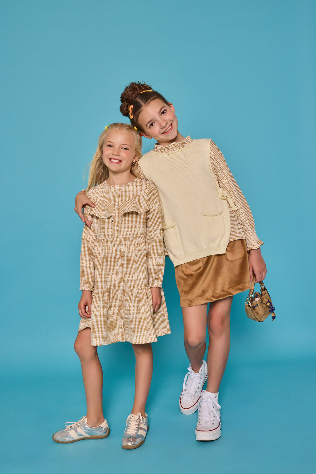 Model on the right can be seen wearing tan/cream pattern woven top paired underneath a cream sweater vest with ties at sides for an elevated look. Paired back with our skort in brown faux suede to complete the look. Model on the left can be seen wearing the matching print in a woven dress with buttons down the front and ruffles at bust for an elevated look. 