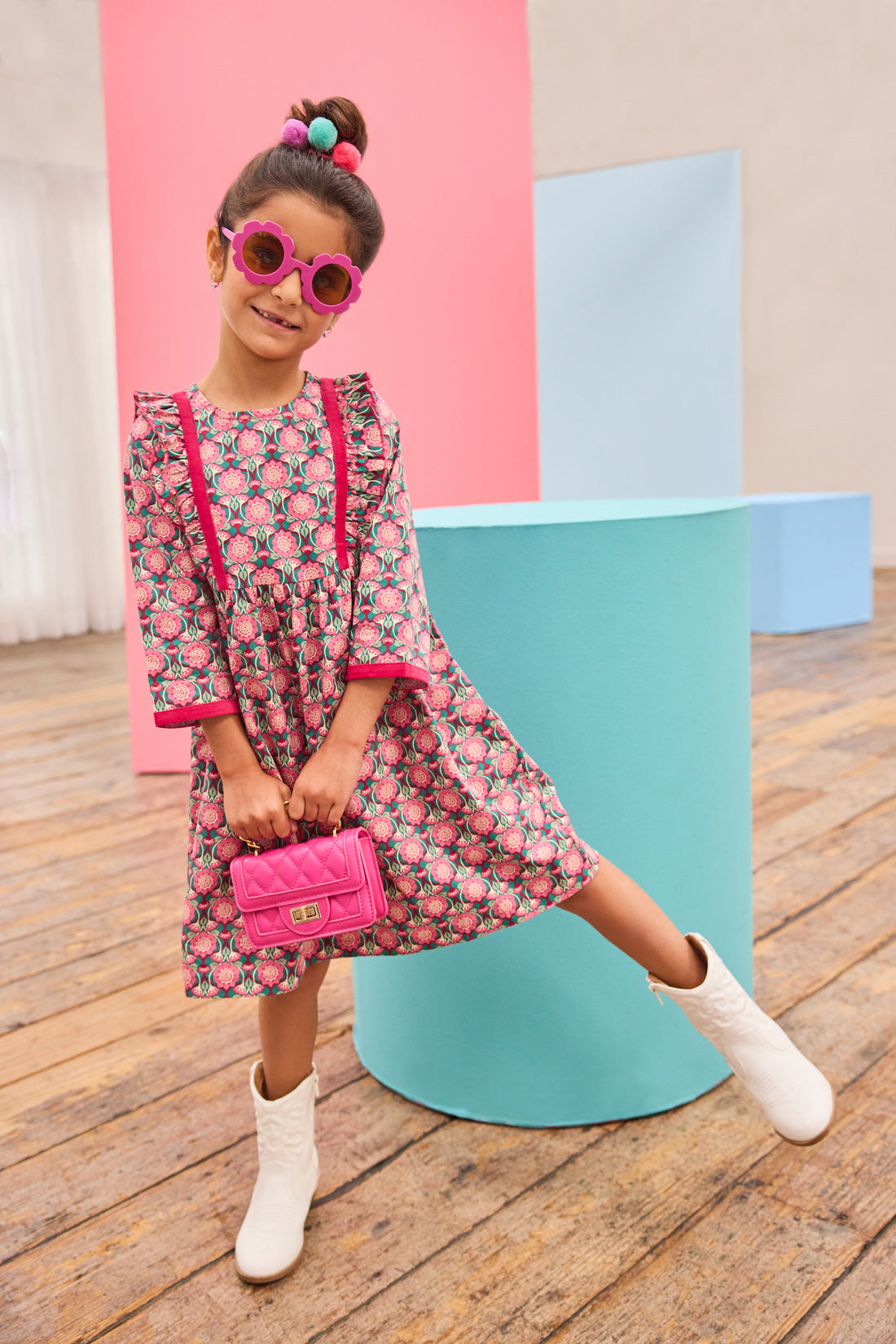 Model can be seen wearing pink/green/green floral pattern woven dress that features velour detail along bottoms of sleeves and trim of chest ruffle detail for an elevated look.
