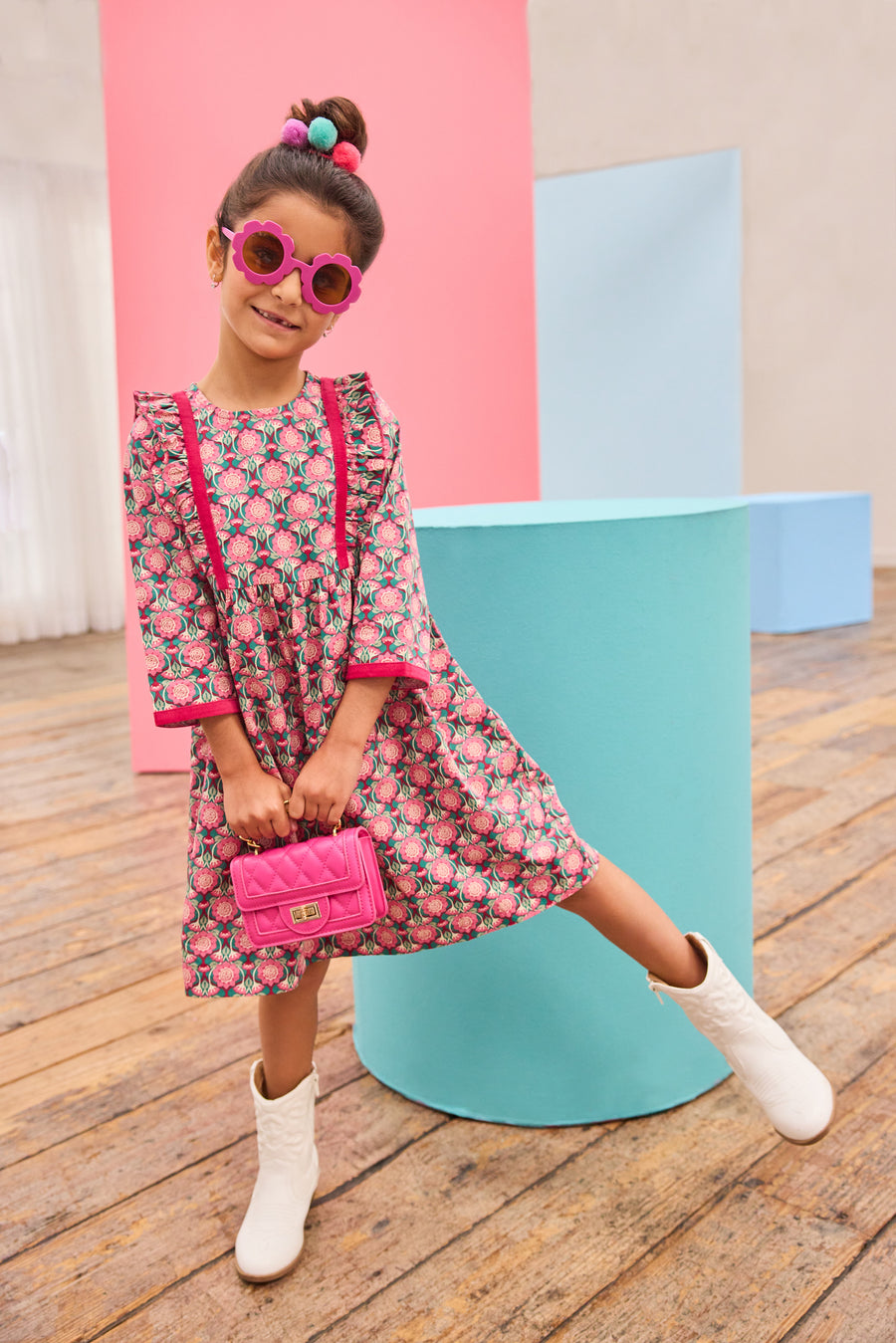 Model can be seen wearing pink/green/green floral pattern woven dress that features velour detail along bottoms of sleeves and trim of chest ruffle detail for an elevated look.