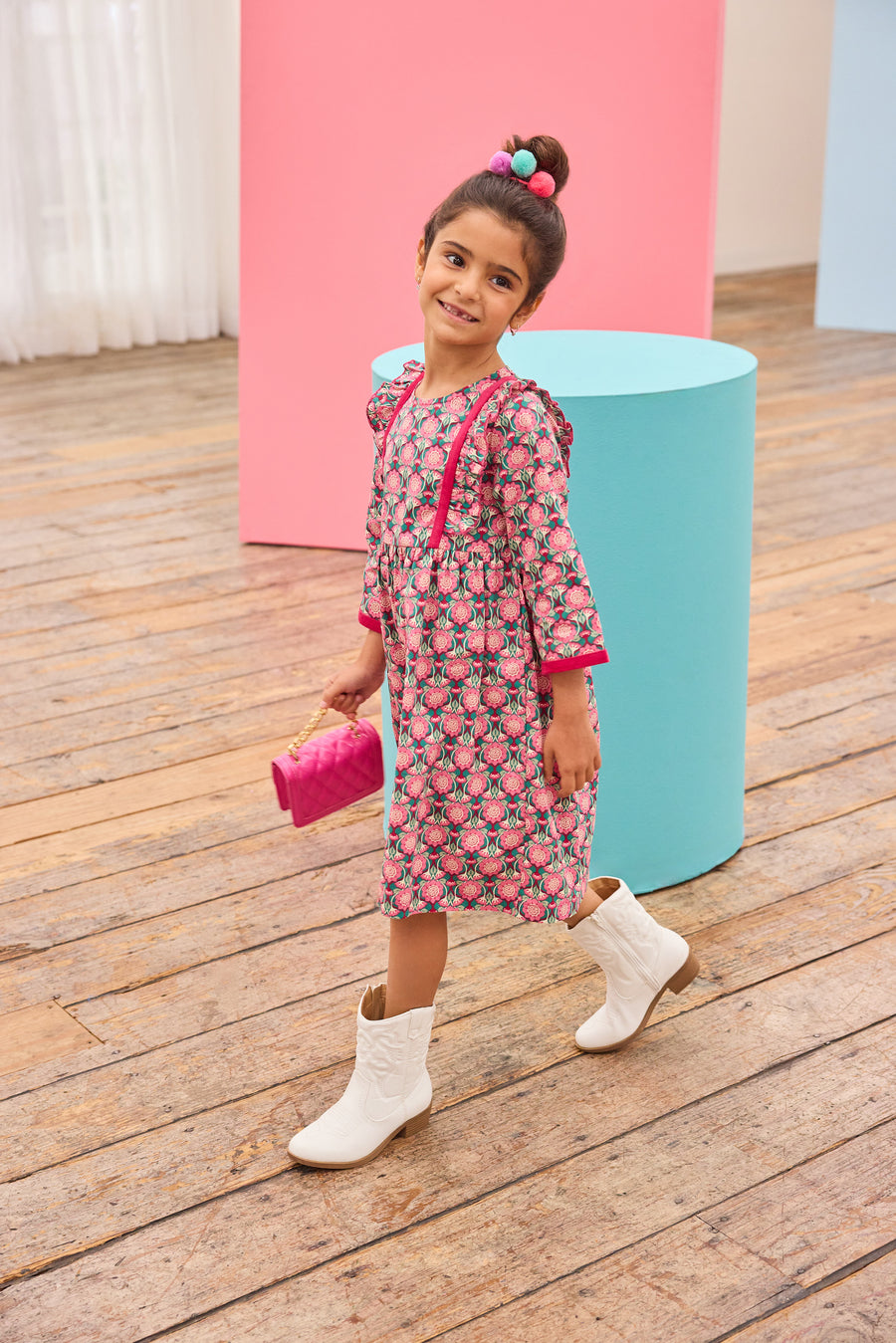 Model can be seen wearing pink/green/green floral pattern woven dress that features velour detail along bottoms of sleeves and trim of chest ruffle detail for an elevated look.