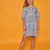 Model can be seen wearing blue floral corduroy dress with 3/4 sleeves and ric rac trim detail in light blue for an elevated look. 