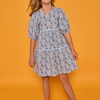 Model can be seen wearing blue floral corduroy dress with 3/4 sleeves and ric rac trim detail in light blue for an elevated look. 
