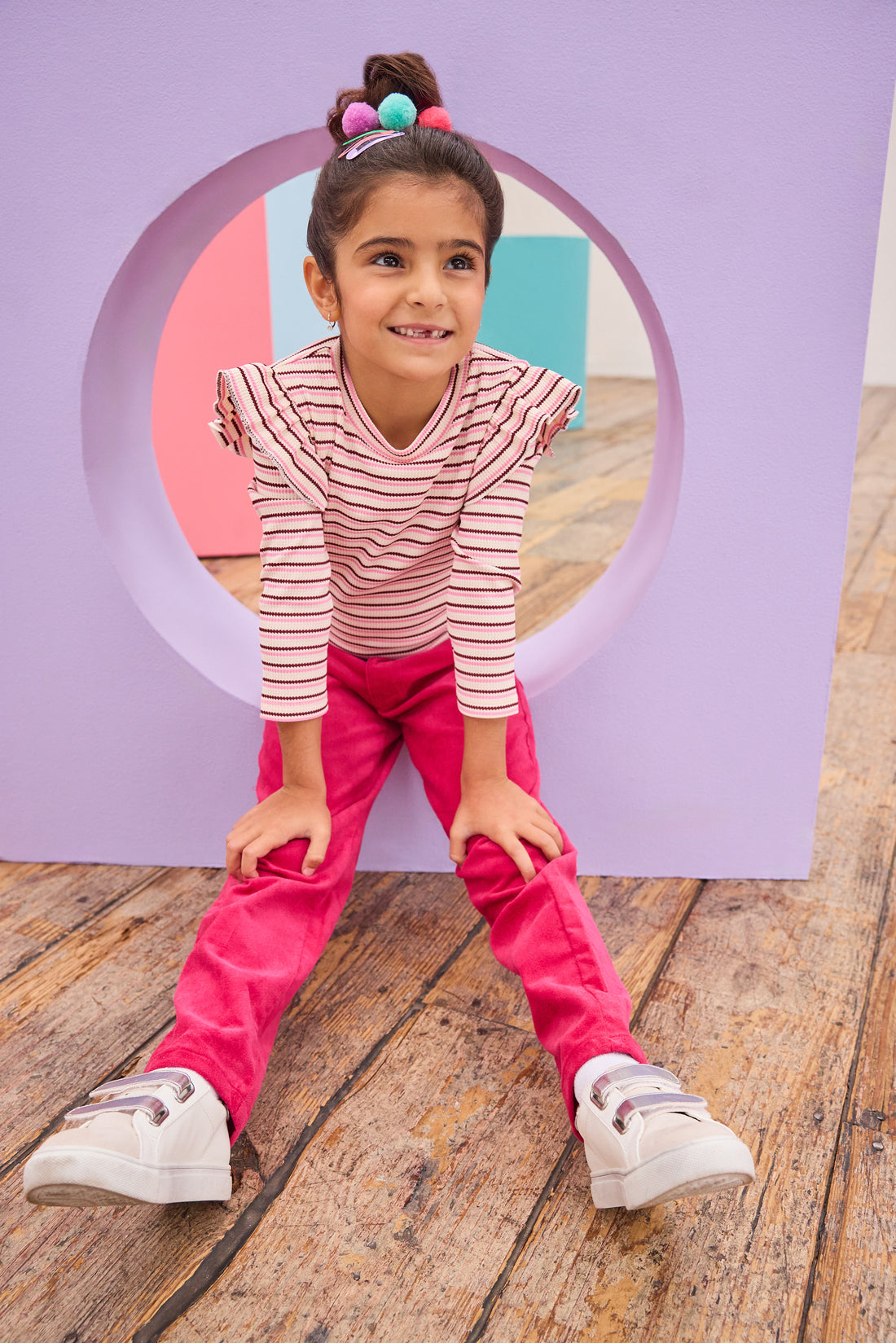 Model can be seen wearing a soft striped knit long sleeve shirt in a pink/maroon/cream stripe. Top features ruffle/angle sleeve detail to elevate the look. Pairs back perfectly with cranberry color velvet pants to complete the look. 