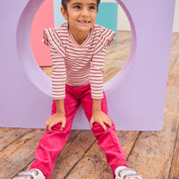 Model can be seen wearing a soft striped knit long sleeve shirt in a pink/maroon/cream stripe. Top features ruffle/angle sleeve detail to elevate the look. Pairs back perfectly with cranberry color velvet pants to complete the look. 
