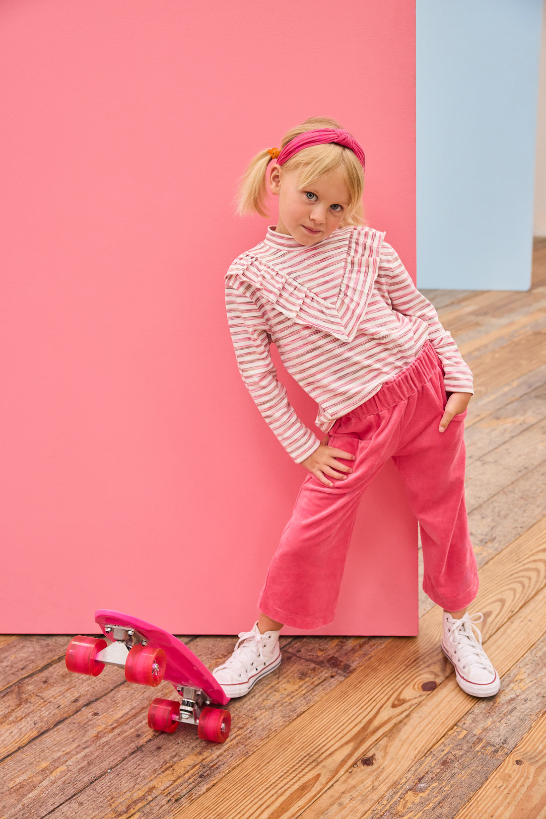 Model can be seen wearing a knit long sleeve stripe  top that features a v-ruffle detail down the center of the shirt for an elevated look. Paired back perfectly with velour pants to complete the look. 