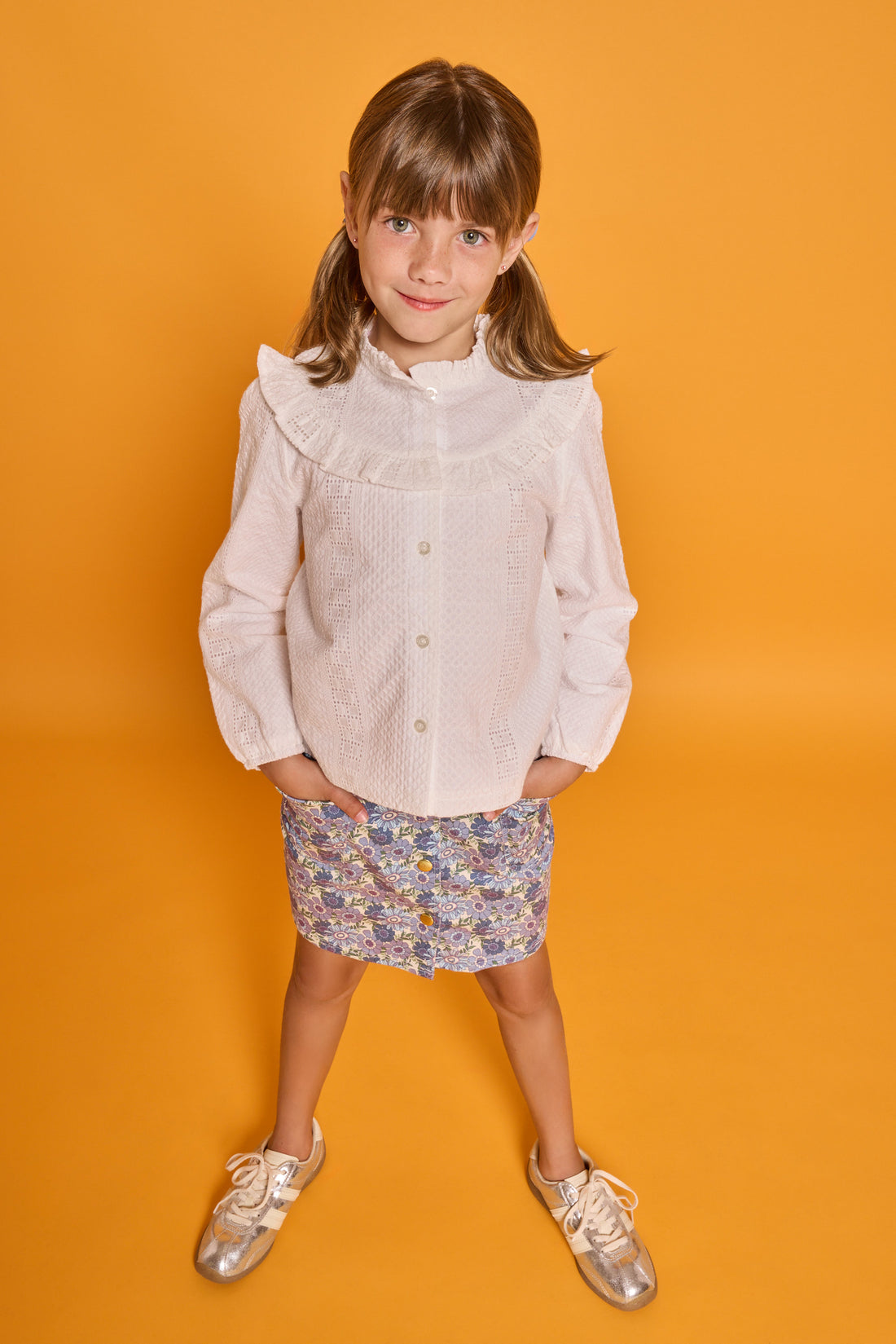 Model can be seen wearing white embroidered woven top with buttons down the front paired back with our corduroy skirt in a blue floral print. 