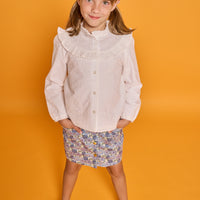 Model can be seen wearing white embroidered woven top with buttons down the front paired back with our corduroy skirt in a blue floral print. 