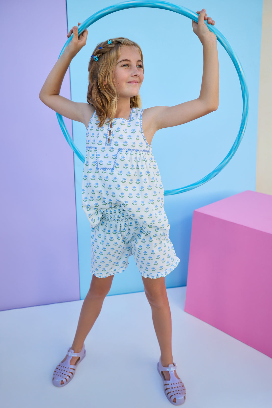 Model can be seen wearing woven blue and green floral print top that features button closure down the front and a beautiful blue embroidered trim to elevate the look. Top pairs back perfectly with shirred shorts in the same floral print to complete the look. 