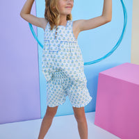 Tween model can be seen wearing white shirred shorts in a green/light blue floral print. Shorts feature smocking along waist and ruffle edges to elevate the look. Paired back perfectly with the woven tank top in the same floral print to complete the look. 