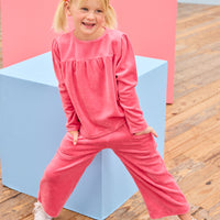 Model can be seen wearing pink velour pants that feature an elastic waistband and functioning pockets in the front of pants. Pants pair pack perfectly with long sleeve velour top in the matching pink color to complete the look. 