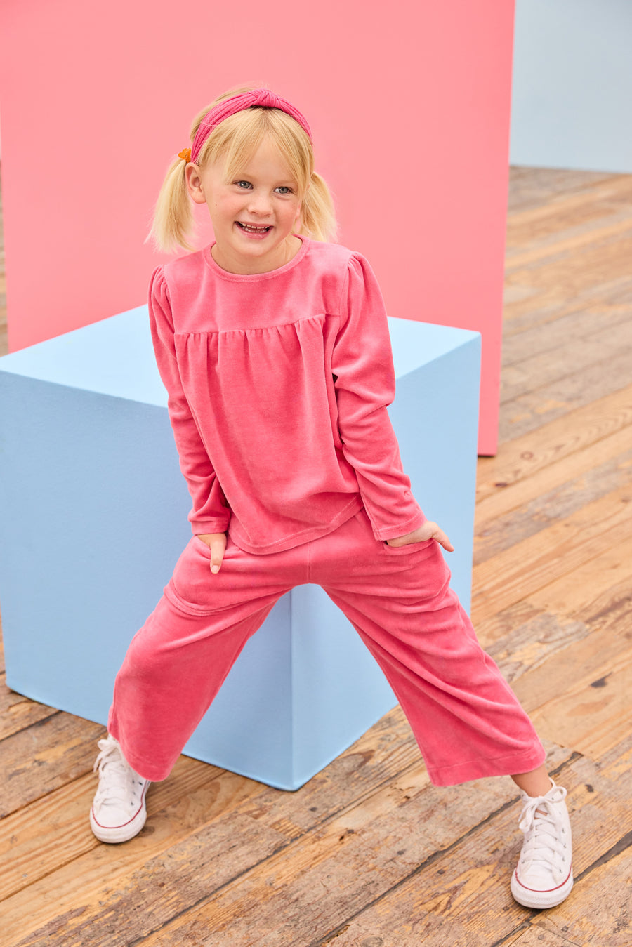 Model can be seen wearing velour long sleeve pink top that features slight pleating detail across bust for an elevated look and button closure along back of shirt. Pair back perfectly with the matching velour pants to complete the look. 