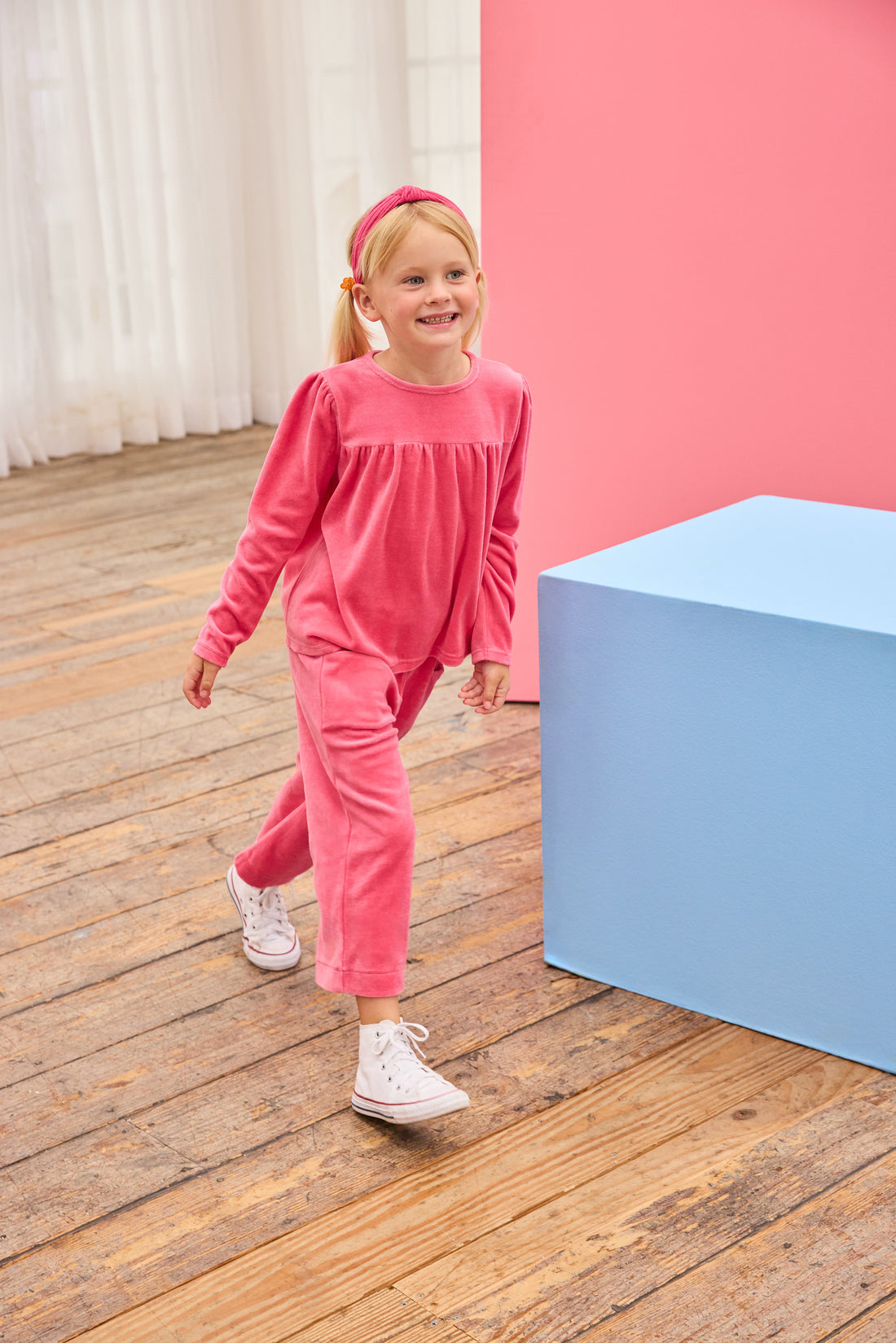 Model can be seen wearing pink velour pants that feature an elastic waistband and functioning pockets in the front of pants. Pants pair pack perfectly with long sleeve velour top in the matching pink color to complete the look. 
