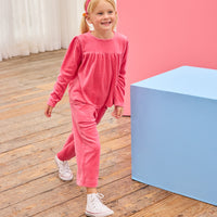 Model can be seen wearing pink velour pants that feature an elastic waistband and functioning pockets in the front of pants. Pants pair pack perfectly with long sleeve velour top in the matching pink color to complete the look. 