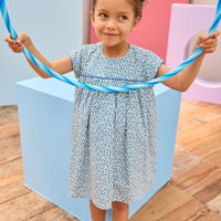 Model can be seen wearing a woven short sleeve dress in a gorgeous blue floral print that features button closures along back and blue trim detail across bust and along sleeves for an elevated look. 