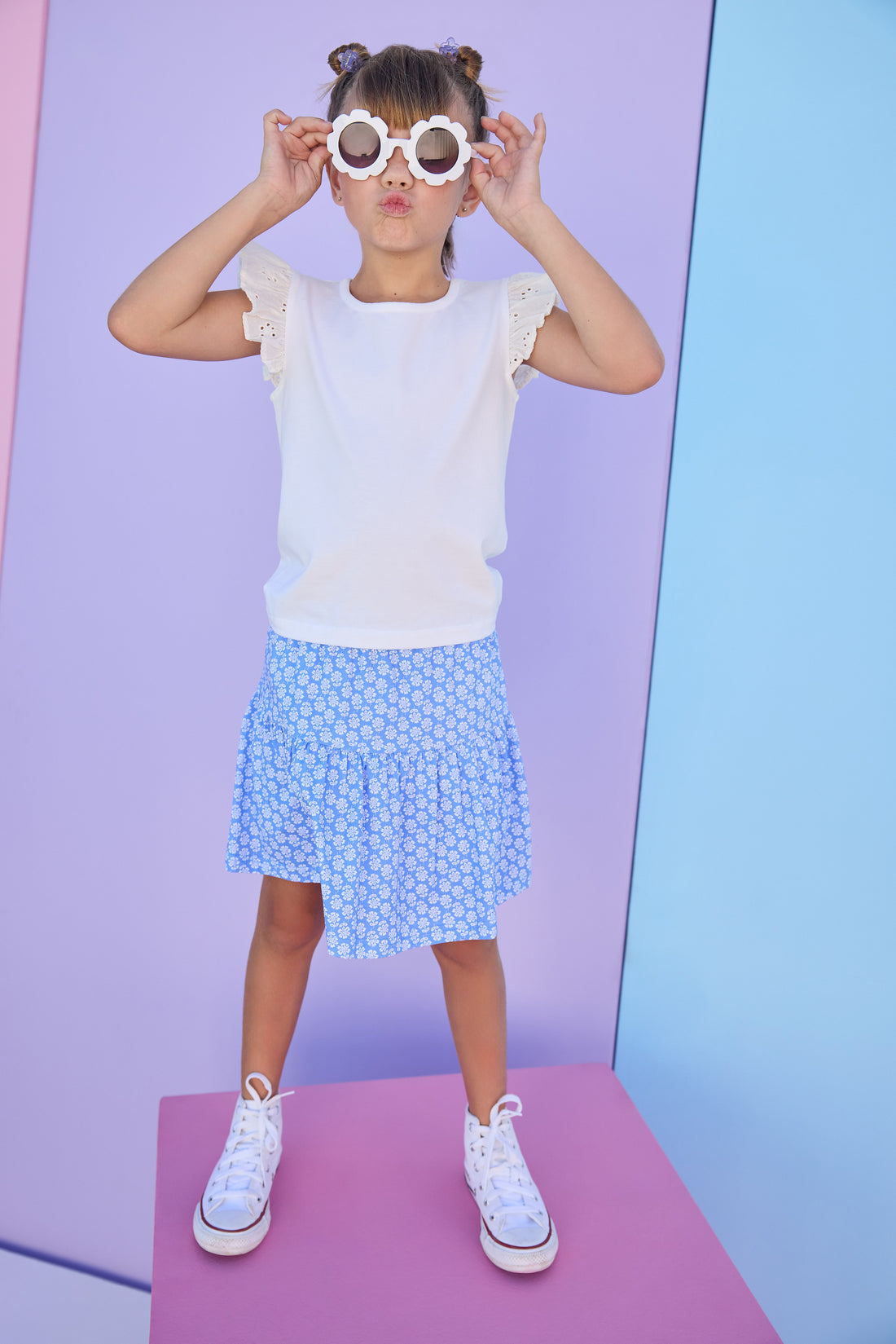 Model can be seen wearing a blue knit skort with a white floral design. Skort features an elastic waistband and built in shorts for a comfy but secure fit. Skort pairs back perfectly with a white knit t-shirt that features eyelet detail on the angel sleeves. 