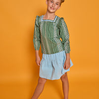 Model can be seen wearing woven long sleeved top with square neckline in a blue/white/green floral print. Paired back perfectly with the light blue corduroy skort to complete the look. 