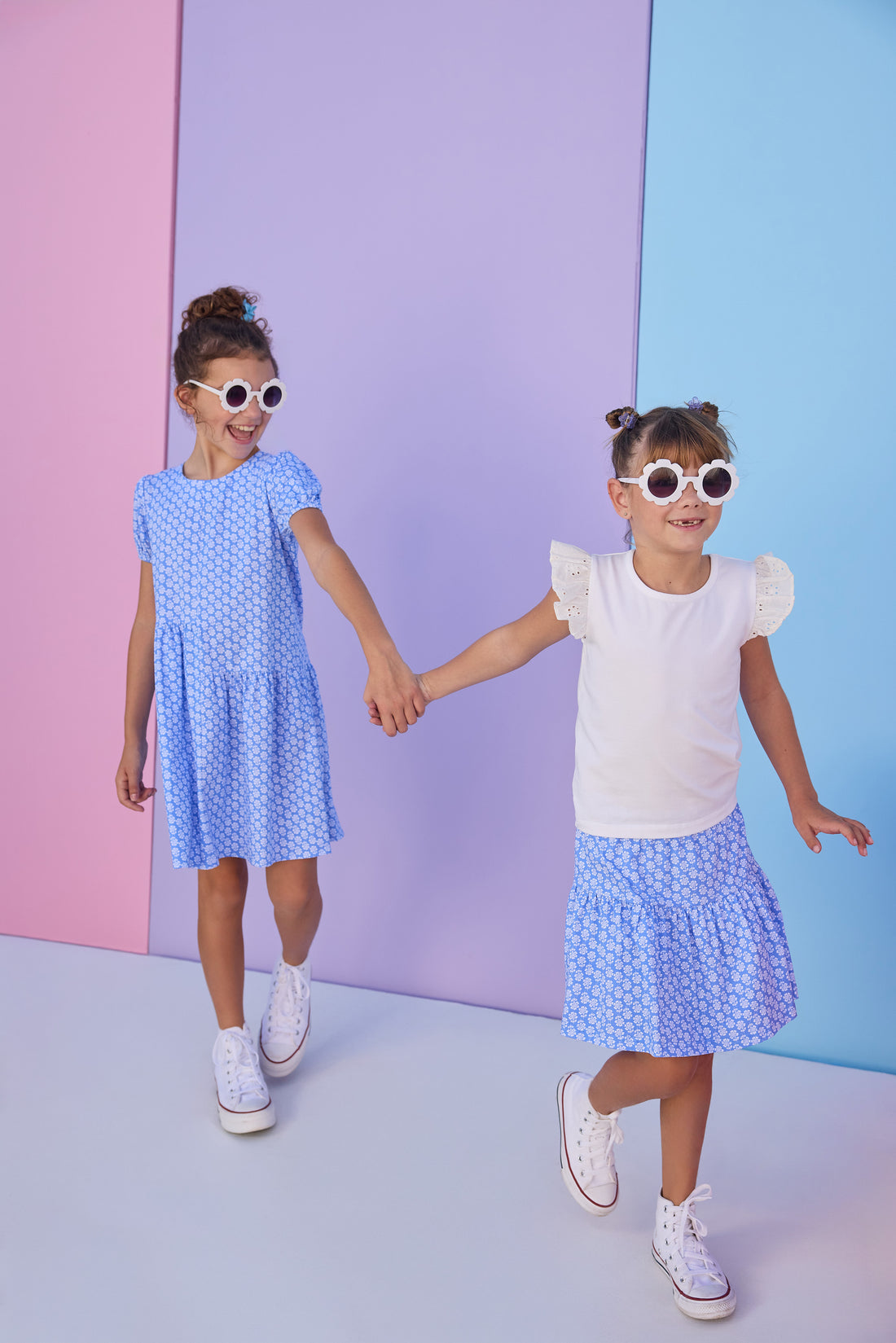 Model on right can be seen wearing a blue knit skort with a white floral design. Skort features an elastic waistband and built in shorts for a comfy but secure fit. Skort pairs back perfectly with a white knit t-shirt that features eyelet detail on the angel sleeves. Model on left can be seen wearing the same blue/white floral print knit fabric in a dress for a matching sister moment. 