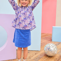 Model can be seen wearing a royal blue velour skort that features an elastic waistband, built in shorts, and two functioning pockets in the front of skort. Pair skort back with purple/blue/white floral top to complete the look. 