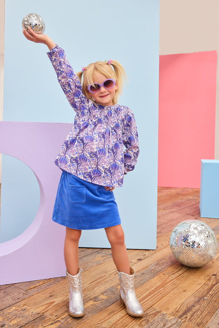 Model can be seen wearing a royal blue velour skort that features an elastic waistband, built in shorts, and two functioning pockets in the front of skort. Pair skort back with purple/blue/white floral top to complete the look. 