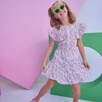 Model can be seen wearing a woven dress in a pink/green floral print. Dress features angel sleeves, button closure down the front, and tier details to elevate the look. 