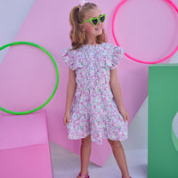 Model can be seen wearing a woven dress in a pink/green floral print. Dress features angel sleeves, button closure down the front, and tier details to elevate the look. 