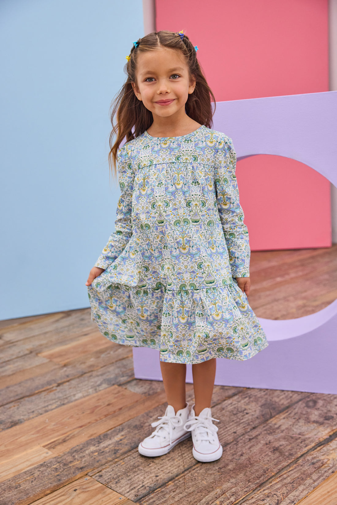 Model can be seen wearing woven long sleeve dress in a beautiful aqua/blue/green/yellow floral print.
