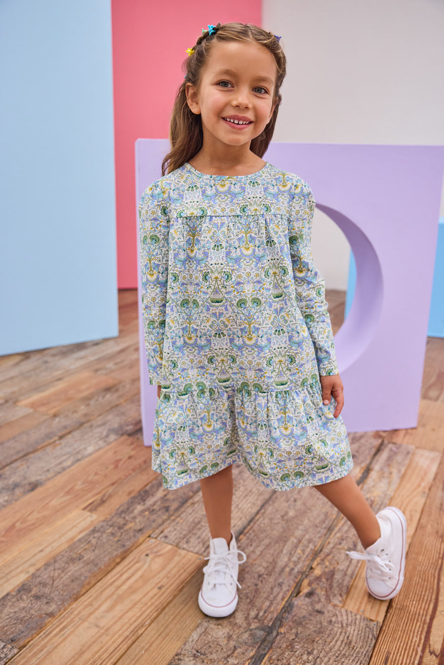 Model can be seen wearing woven long sleeve dress in a beautiful aqua/blue/green/yellow floral print.