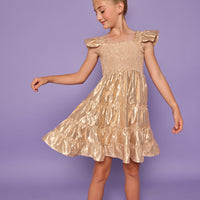 Model can be seen wearing gold metallic lurex that features smocking across bust and angel sleeve sleeves for an elevated look. 