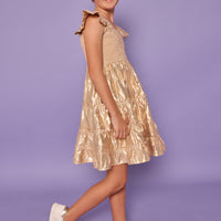 Model can be seen wearing gold metallic lurex that features smocking across bust and angel sleeve sleeves for an elevated look. 